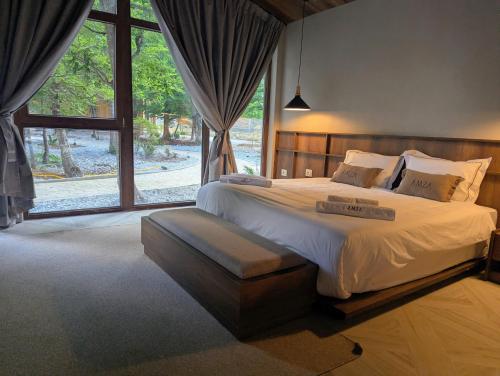 a bedroom with a large bed and a large window at AMZA Valbona Mountain Retreat in Valbonë