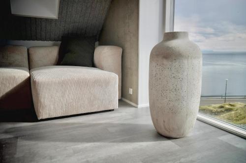 a large white vase sitting in front of a window at Beitisstova - Mesmerizing Sea & Mountain Views in Stykkið