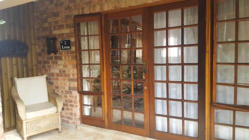a glass door with a chair next to a brick wall at Aark Guest Lodge in Vanderbijlpark