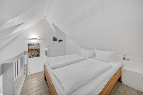 a bedroom with white walls and a bed with white sheets at Wattkieker-Stedum in Rantum
