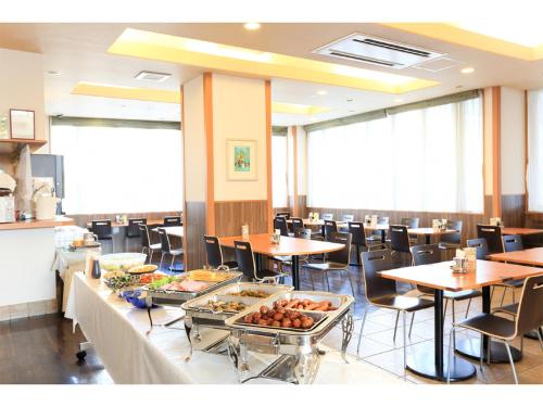 a restaurant with tables and chairs with food on display at Smile Hotel Shiogama in Shiogama