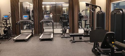 a gym with a bunch of treadmills and mirrors at Double Room with Private Bathroom near Dubai in Sharjah