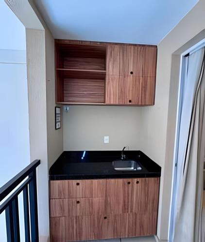 a kitchen with a sink and wooden cabinets at Até 4 Hóspedes, Elevador, Varanda C/Frente Piscina Jr Catito in Brasília