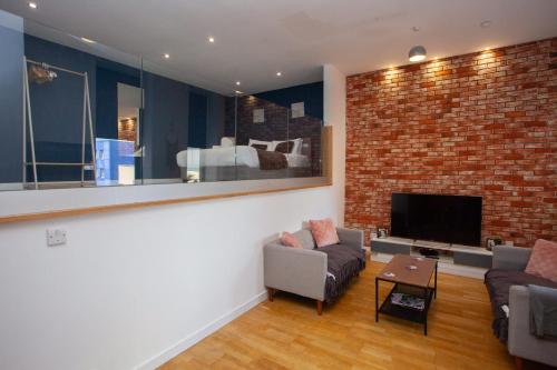 a living room with a brick wall and a tv at Stunning City Centre Duplex in Glasgow