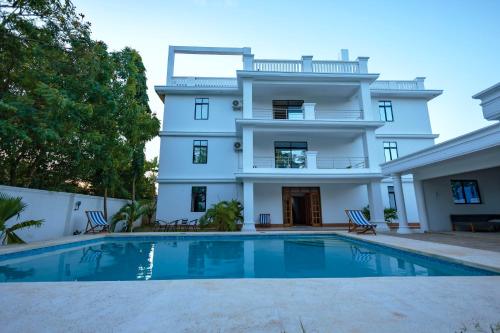 a white house with a swimming pool in front of it at Diani Luxe Villa 1bdr A, 600m from the beach in Galu