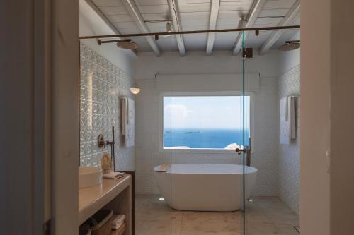a bathroom with a bath tub and a window at Birdhouse Private Luxury Villa in Agios Ioannis Mykonos