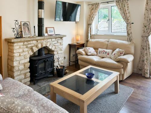 a living room with a couch and a fireplace at Rose Cottage in Upper Rissington