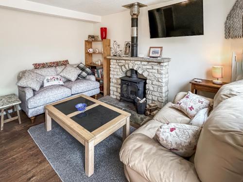 a living room with a couch and a fireplace at Rose Cottage in Upper Rissington