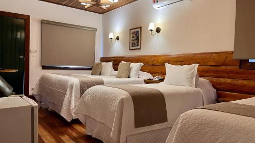 a hotel room with three beds in a room at Hotel Savoy Excellence in Campos do Jordão