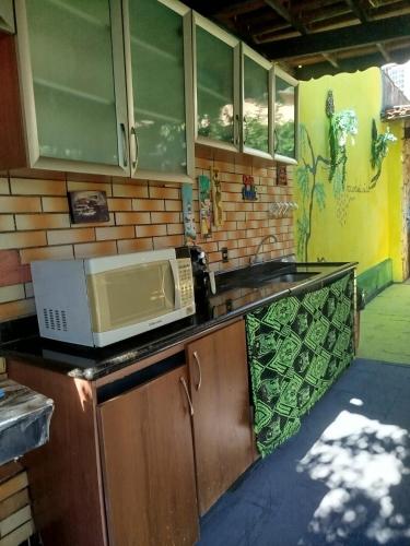 a kitchen with a sink and a microwave on a counter at Casa com Natureza in Goiânia