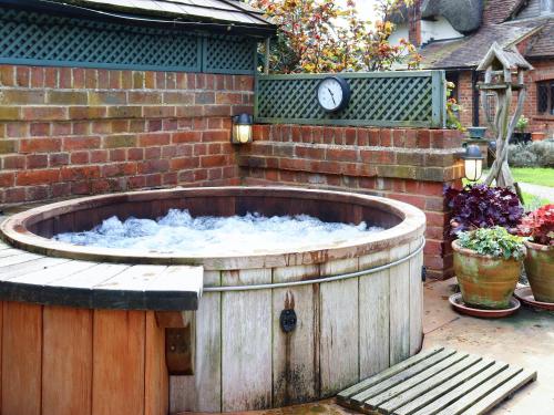 a hot tub with a clock on a brick wall at Pond Cottage in Alton