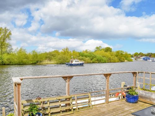 a boat on a river with a wooden pier at Evening Glory in Brundall