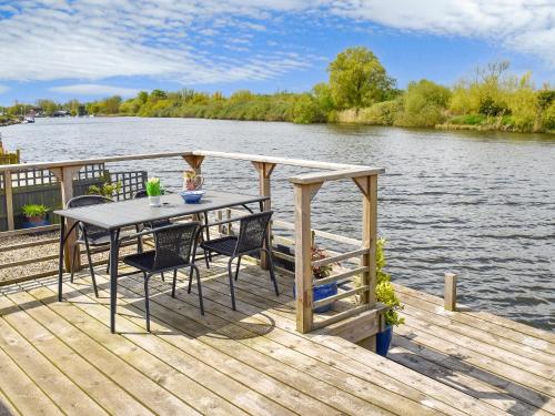 a wooden dock with a table and chairs on the water at Evening Glory in Brundall