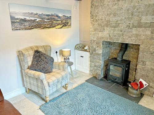 a living room with a stone fireplace and a chair at Cosy Cottage in Portinscale
