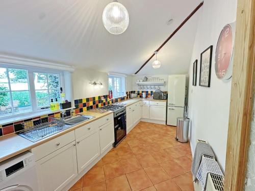 a large kitchen with white cabinets and a tile floor at Rectory Cottage in Isham
