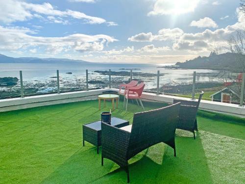 a balcony with chairs and a table on the grass at South Bay Cottage in Saasaig