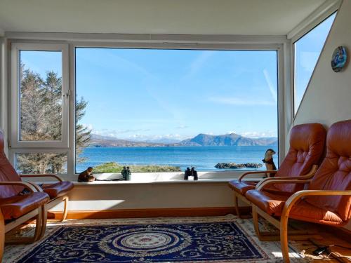 a room with a large window with a view of the water at South Bay Cottage in Saasaig