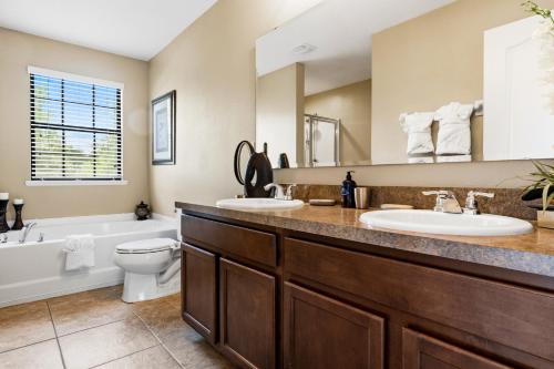 a bathroom with two sinks and a tub and a toilet at Family Friendly - South Facing Pool - Game Room - Gated - Near Disney in Davenport