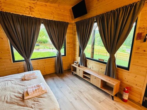 a bedroom with a bed and large windows at Wood Nest Curtea de Argeș - Cabană de vacanță în natură in Curtea de Argeş