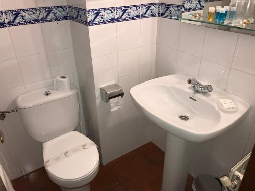 La salle de bains blanche est pourvue de toilettes et d'un lavabo. dans l'établissement Hotel Rural Tia Margot, à Candelario