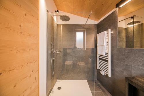 a bathroom with a shower with a glass door at Rotwandwiesen Chalets SKI IN/OUT - 1900mt in Sesto