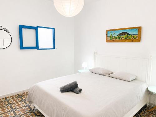 a bedroom with a white bed with two pillows on it at Sol y Mar Surf Camp in Corralejo