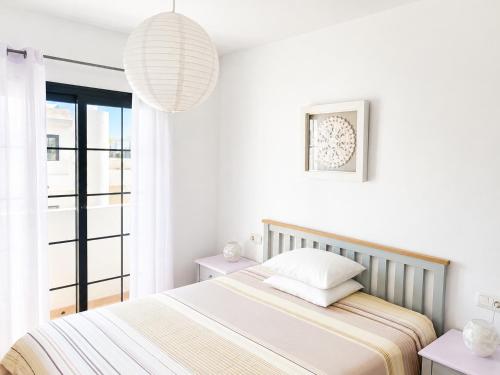 a white bedroom with a bed and a pendant light at Surfers Retreat in Corralejo