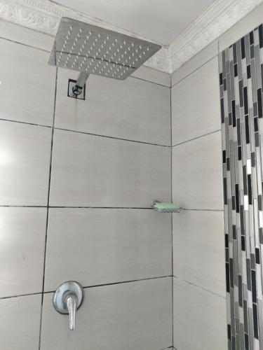 a shower with white tile and a shower head at Eluthando Guesthouse in St Lucia