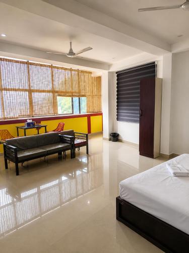 a bedroom with a bed and a couch and a table at Grand Munnar Rooms in Munnar