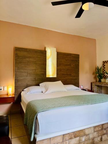 a bedroom with a large bed with a wooden headboard at La Casa de las Lunas in Chichén-Itzá