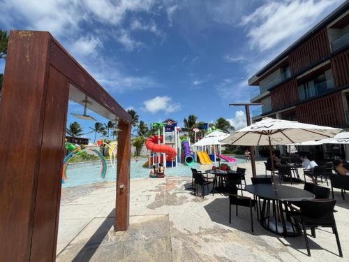 a pool with a water park with tables and umbrellas at Gav Resorts in Ipojuca