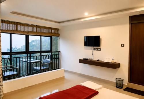 a living room with a balcony with a tv at Grand Munnar Rooms in Munnar