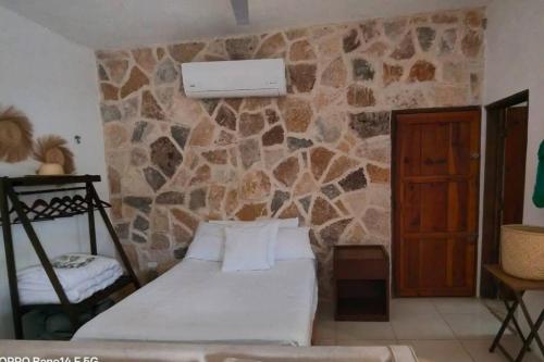 a bedroom with a bed and a stone wall at Precioso chalet en Telchac Puerto in Telchac Puerto