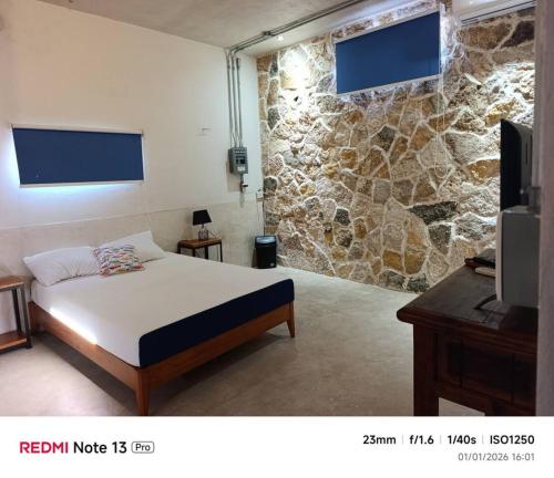 a bedroom with a bed and a stone wall at Departamento comodo en Progreso 1 Recamara 3 personas in Progreso