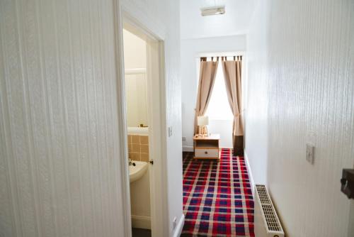 a hallway with a bathroom with a tub and a sink at Ocean Breeze Inn in Eyemouth
