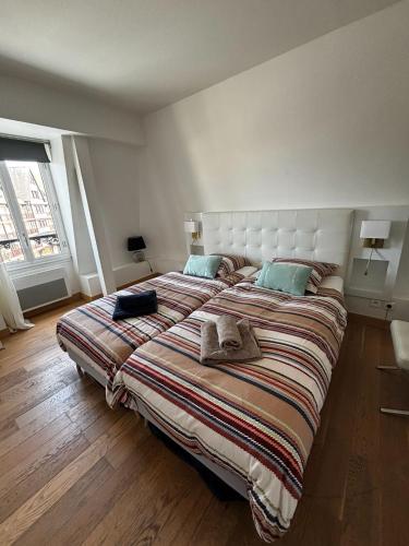a bedroom with a large bed with a striped blanket at Appartements à Deauville dans Triangle d'Or in Deauville