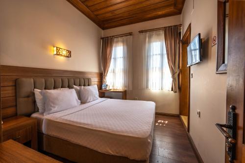 ein Schlafzimmer mit einem Bett mit weißer Bettwäsche und zwei Fenstern in der Unterkunft Armistis Hotel in Mudanya