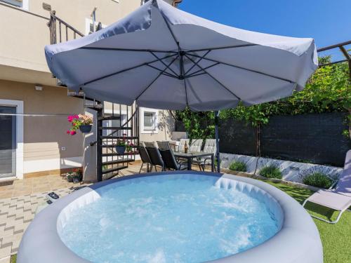an umbrella and a pool with a table and chairs at Apartment L&V by Interhome in Galižana