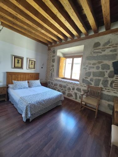 ein Schlafzimmer mit einem Bett und einer Steinwand in der Unterkunft HOTEL EL RASTRO - Palacio Duque de Tamames - in Avila
