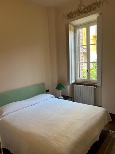 a bedroom with a white bed and a window at Casa Ninni in Tremezzo