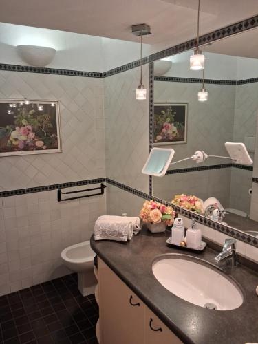 a bathroom with a sink and a toilet and a mirror at Casa Ninni in Tremezzo