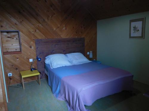 a bedroom with a bed and a wooden wall at Chambres d'hôtes Ferme de Sardonnet in Allouis