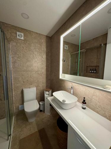 a bathroom with a sink and a toilet and a mirror at Casa Oceano 59 in Costa da Caparica