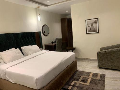 a bedroom with a large bed and a chair at Adwels Hotel&Suites in Akure