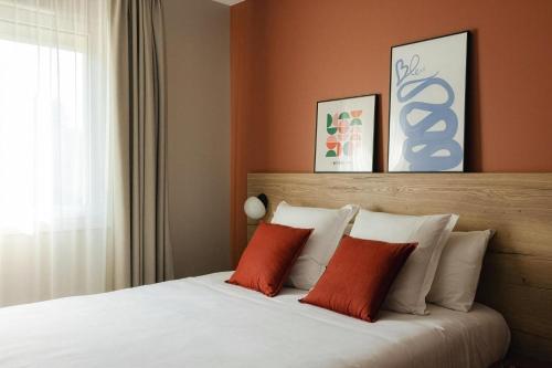 a bedroom with a bed with two red pillows at Sure Hotel by Best Western Tours Sud in Chambray-lès-Tours
