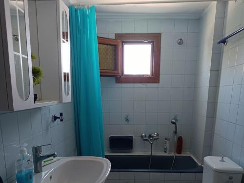 a bathroom with a sink and a blue shower curtain at Thalia in Perea