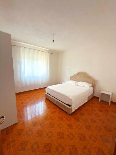 a bedroom with a white bed and a wooden floor at Olive GREEN house in Durrës