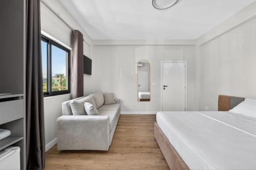a white bedroom with a bed and a couch at Casa Del Sol Seaside Hotel in Durrës