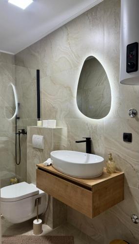 a bathroom with a large white sink and a mirror at Apartmani SARA Bugojno in Bugojno