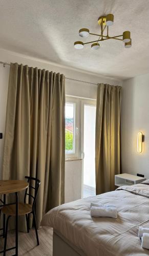 a bedroom with a bed and a table and a window at Apartmani SARA Bugojno in Bugojno